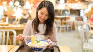 現地のラーメンを食べる女性