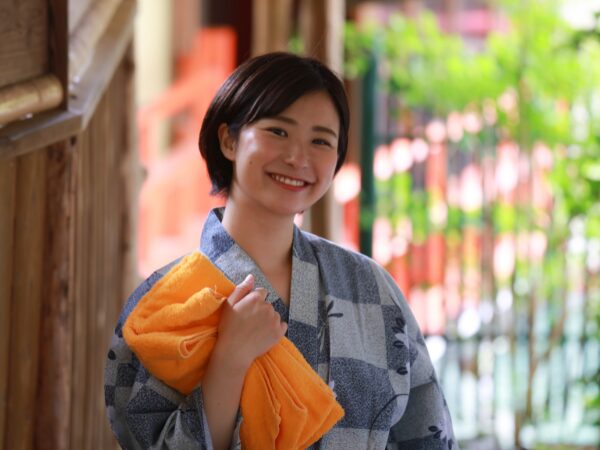 オレンジ色のタオルを持った浴衣姿の女性