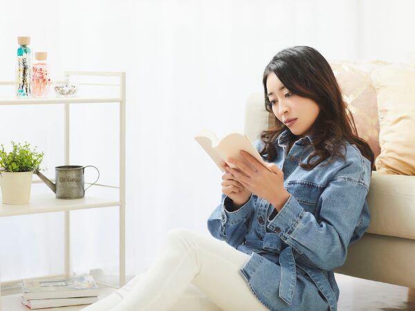 ソファーに寄っかかって本を読む女性