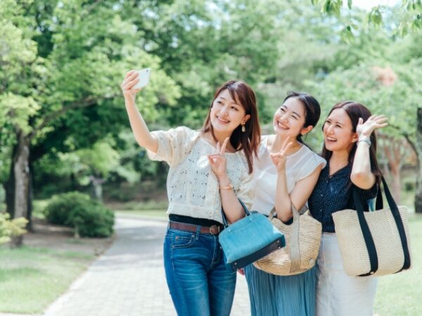 旅行中にスマホで写真を撮る3人組の女性