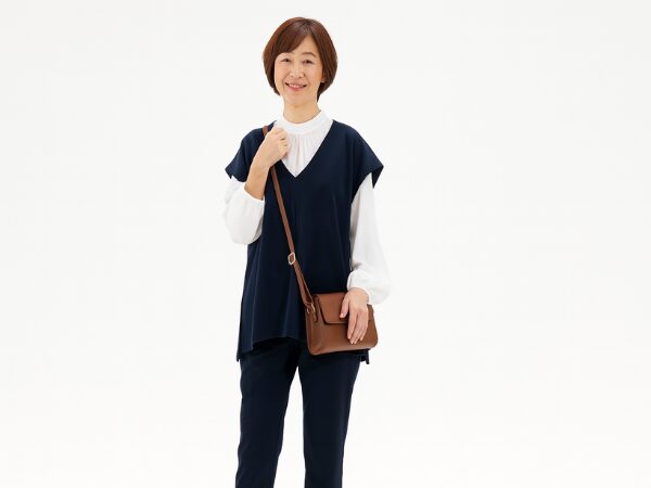 紺色のセットアップ服を着て茶色いショルダーバッグの女性