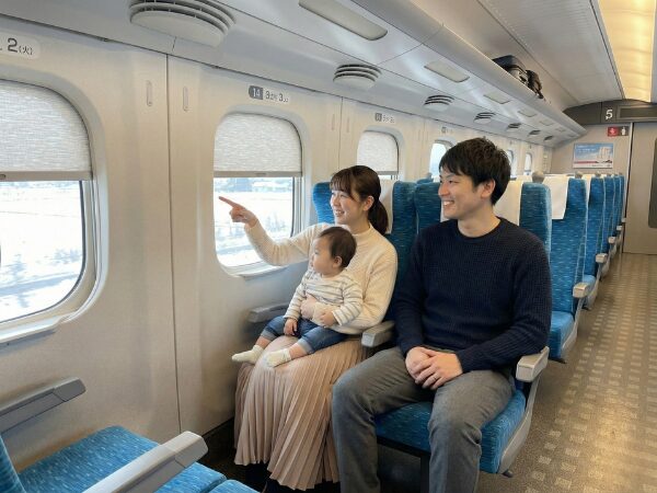 新幹線内から外の景色を指さして見ている3人家族