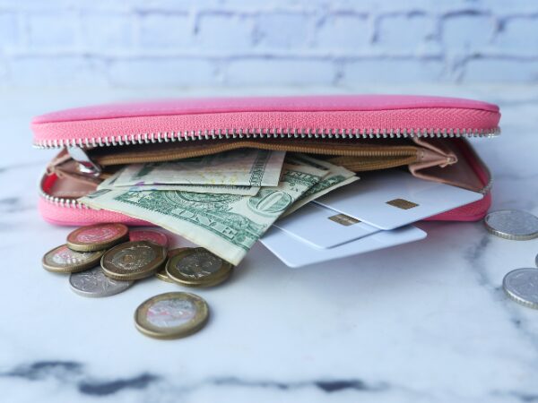 ピンク色の長財布からお札とカードとコインが出ている様子