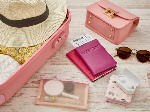 サーモンピンクのスーツケースと麦わら帽子とサングラス等の持ち物